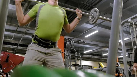 The overweight man does squats with squats with a weight disc for a barbell Video stock 111888428