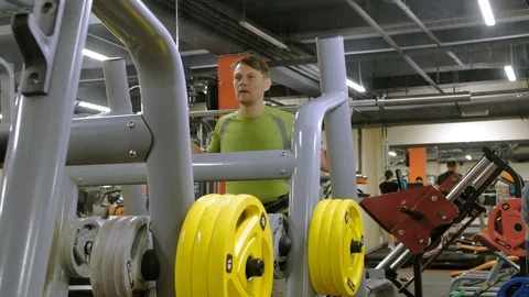 The overweight man does squats with squats with a weight disc for a barbell Video stock 111888640