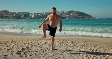 An overweight man does a warm-up on the beach before training. Stock Footage 172142028