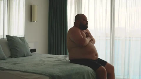 Overweight man feeling bad having seizure, difficulty breathing sitting in bed Stock Footage 250517834