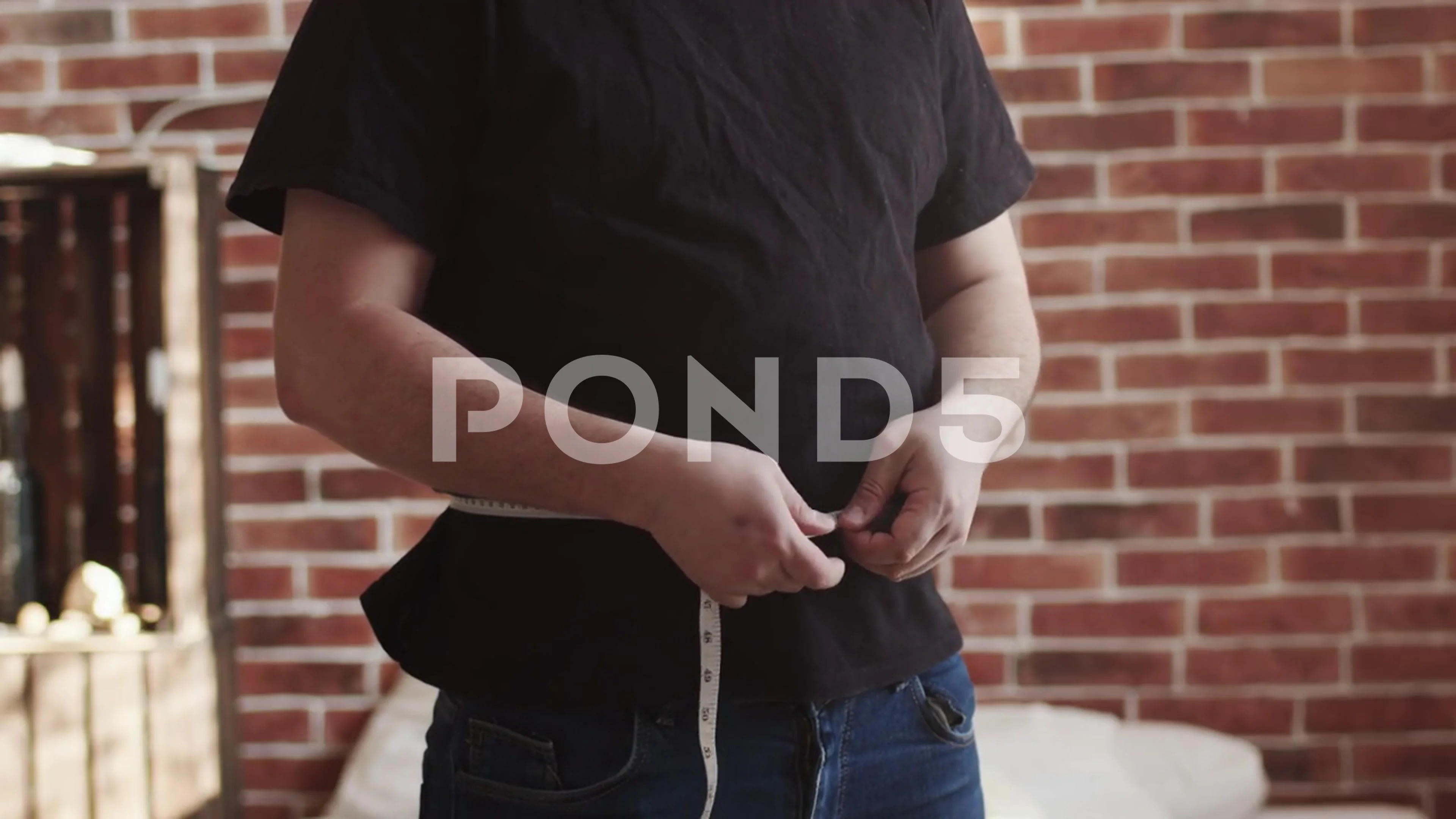 Obese man measuring waist with tape measure - SuperStock