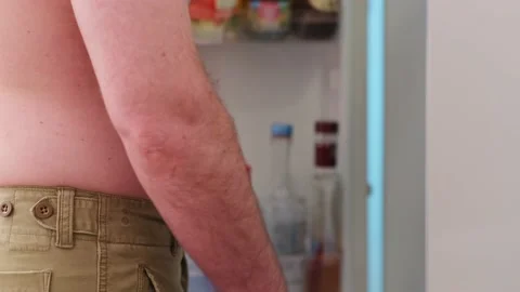 Overweight man opening fridge taking fresh celery. Stockbeeldmateriaal 194371103