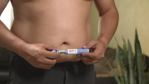 Overweight man preparing pen injection (semaglutide) insulin resistance and Stock Footage 331579505