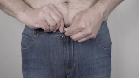 Overweight man trying to button his pants over his big belly. Stock Footage 78657041
