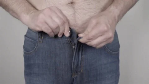 Overweight man trying to button his pants over his big belly. Stock Footage 78657149