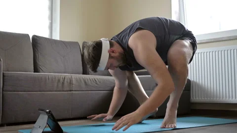 Overweight man is trying to do complex sports exercises. Doing sports online at Stock Footage 131184757