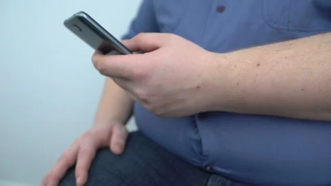 Overweight man typing smartphone message, fitness training program online, diet 库存影片 89444666