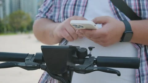Overweight man unlocks an e-scooter using mobile phone app. Male rents electric Stock Footage 255052500
