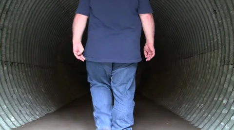 OVERWEIGHT MAN WALKING INTO CORRUGATED CULVERT UNDERPASS Stock Footage 25102477