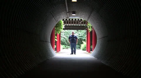 OVERWEIGHT MAN WALKING INTO CORRUGATED UNDERPASS FROM PAGODA Stock Footage 25101690