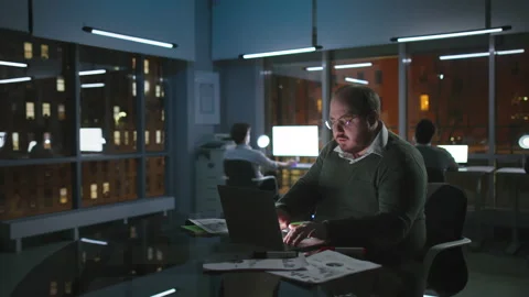Overweight office manager work on computer late in loft office in Manhattan Stock Footage 174614672