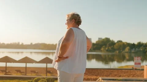 Overweight pensioner resting with hands on hips enjoying lake view. fitness and 库存影片 340992141