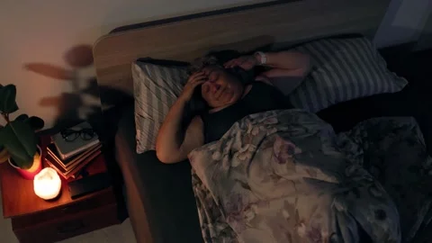 Overweight Tired Elderly Lady Waking Up with Bad Headache in Dark Bedroom Stock Footage 338034766