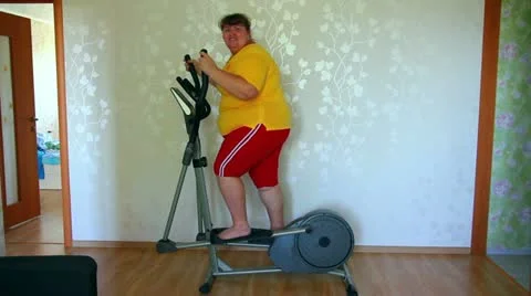 Overweight woman exercising on trainer ellipsoid Stock Footage