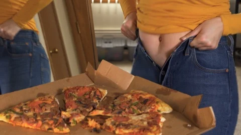 Overweight woman having problems with fitting in small jeans and buttoning them Stock Footage 125406737