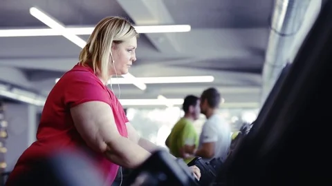 Overweight woman walking on treadmill in modern gym Stock Footage