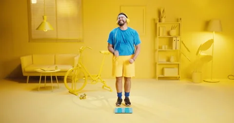 Overweight young man measuring his weight on scales and looks angry after fail Stock Footage 165866991
