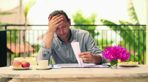 Overwhelmed, sad man checking bills by the table on terrace HD Vídeo Stock 42182796