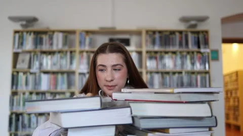 Overwhelmed student feels lost among books while preparing for exams Stock Footage 341656418