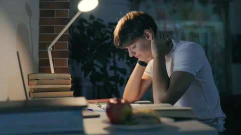 Overworked adolescent guy suffers from neck stiffness doing homework. Stock Footage 345209891