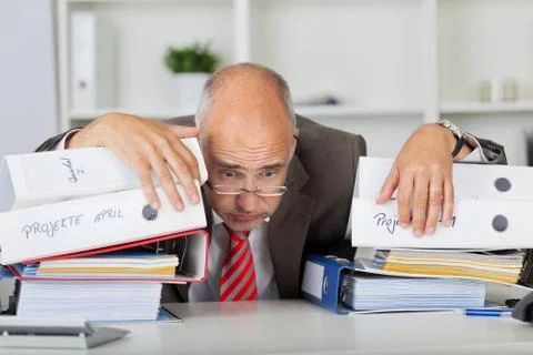 Overworked businessman leaning on stack of binders Stock Photos