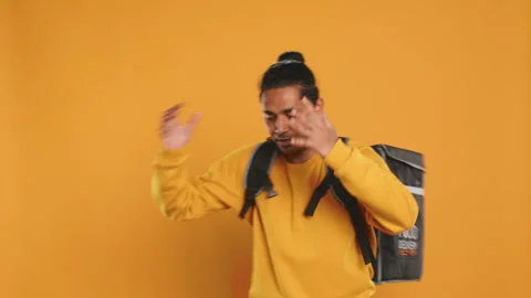 Overworked courier carrying huge stack of pizza boxes, studio background Video stock 274316143