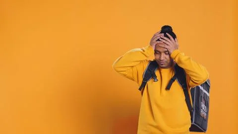 Overworked courier carrying huge stack of pizza boxes, studio background Stock Photos