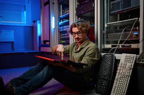 Overworked data center engineer using keyboard on supercomputer server room Stock Photos