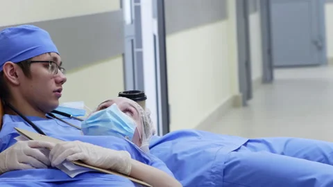 Overworked Doctors Drinking Coffee and Resting in Hospital Corridor Stock Footage 138116962