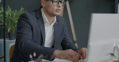 Overworked employee Middle Eastern man using computer typing then taking off 動画素材 237691931