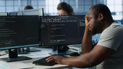 Overworked engineer falling asleep while typing on computer in server hub Stock Photos