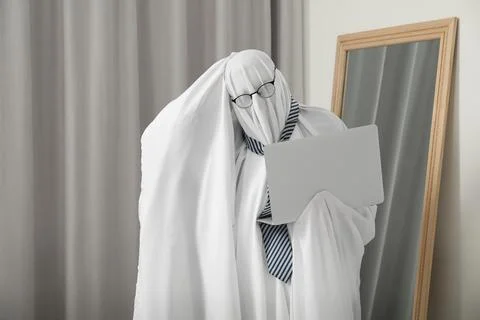 Overworked ghost. Man in white sheet using laptop at home Stockfoto's