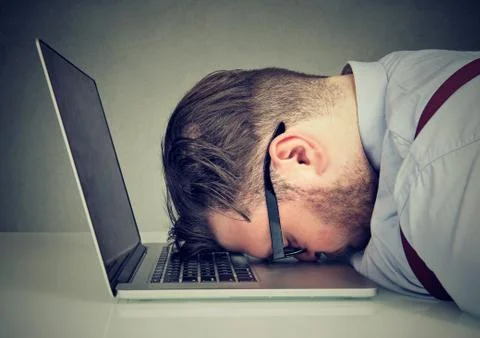 Overworked man lying on laptop Stock Photos