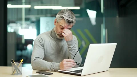 Overworked mature gray haired bearded businessman in glasses tired working  Stock Footage 232580024