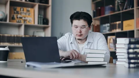Overworked student falling asleep at a library desk Vídeo Stock 331523322