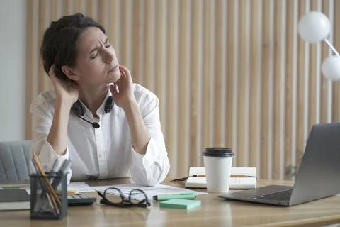 Overworking remote call center operator lady suffers from fatigue and neck pain Foto stock