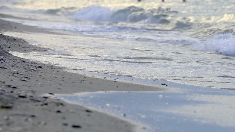 Ow point of view over an out-of-focus pebbled beach with a splashing wave, ba Stock Footage 117825003