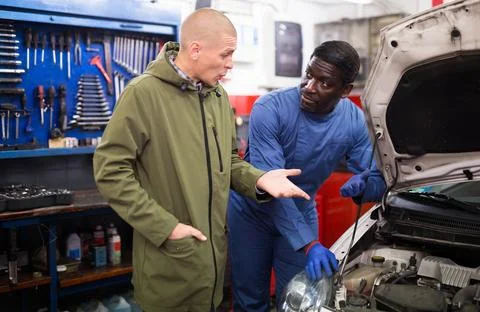 Owner of car explains the problem with car engine to mechanic of the car service 스톡 사진