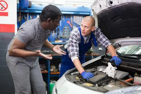 Owner of car explains the problem with car engine to mechanic of the car service Stock Photos