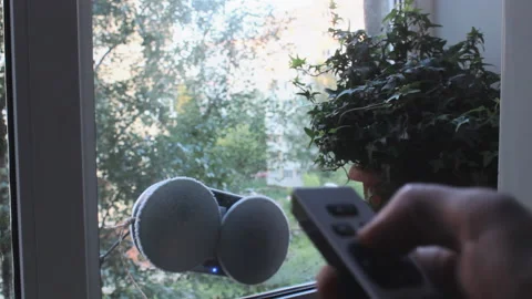 Owner of the house starts from remote control cleaning robot on window Stock-Footage 205318563