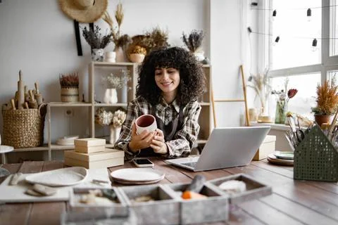 Owner of pottery workshop updates database of items that sold on website. Stock Photos