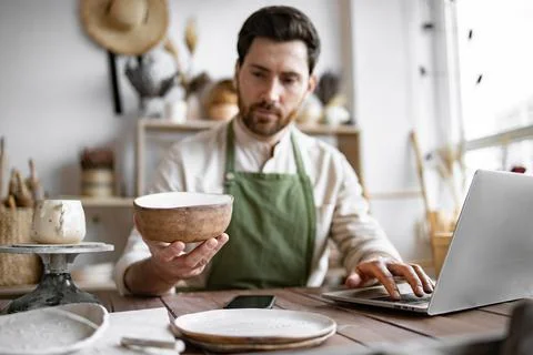 Owner of pottery workshop updates database of items that sold on website. 스톡 사진