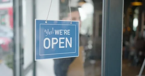 Owner is reaching, unhooking red CLOSED sign on door and hanging blue OPEN sign Stock Footage 337731854