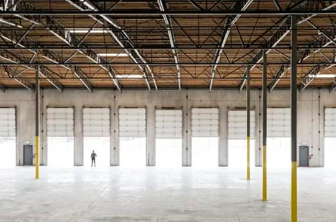 Owner silhouetted and standing in a loading dock door for a new empty warehouse. Stock Photos