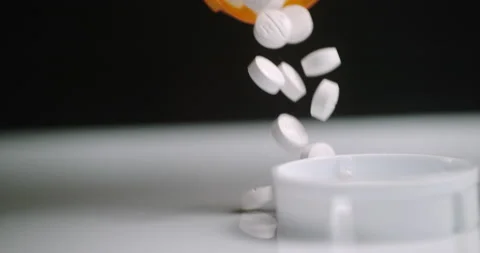 Oxycodone pills fall from a bottle in slow motion, symbolic of addiction. Stock Footage 167322504