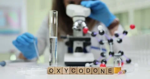 Oxycodone word formed near molecular model and lab glass cylinder 스톡 동영상 314124106