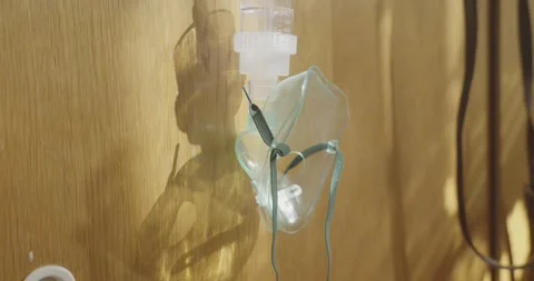 Oxygen Breathing Mask Casting Ominous Shadows Beside Bed in Cinematic Scene Stock Footage 344348460