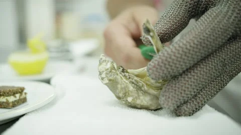 An oyster is cracked open in the kitchen of a fine dining restaurant Stock Footage 328836858