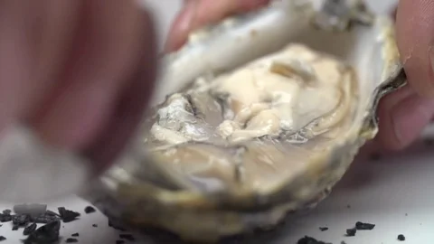 The oyster is turned over with a knife in the shell. Stock Footage 77676986