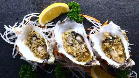 Oysters in Shells Fried with Garlic and Lemon on Black Textured Slate Background Stock Footage 138270948